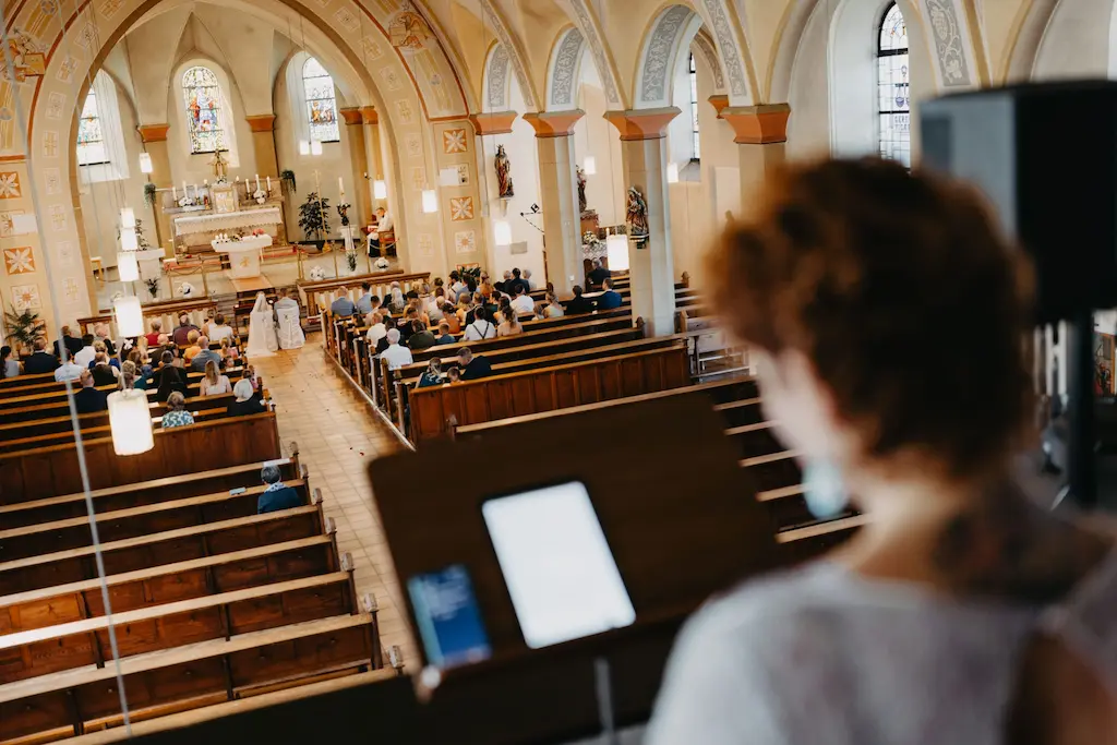 Blick von Sängerin und freier Rednerin Corinna Portz aus dem Saarland auf eine kirchliche Trauung in einer festlich geschmückten Kirche. Sie begleitet das Brautpaar und die Gäste mit emotionalem Gesang und persönlichen Worten – in Deutschland, Österreich, der Schweiz und weltweit.